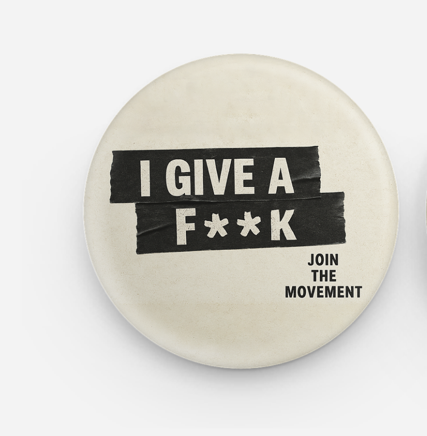 Round off-white button pin with black tape blocks reading I GIVE A F**K and small text JOIN THE MOVEMENT